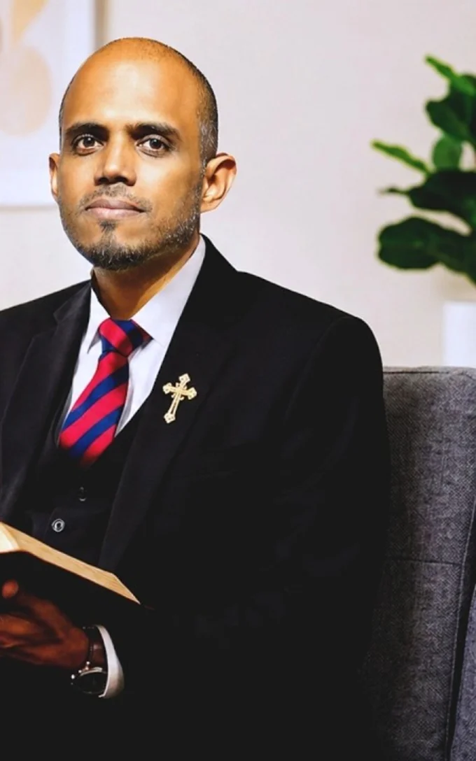 Rev. Dr. Jim Reuben Elliot seated with an open Bible